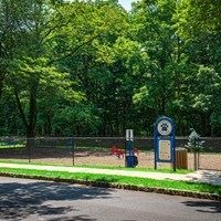 A sign with a blue border and white background is in front of a fence.
